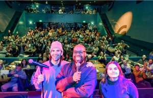 Thumbnail photo of Comedian Dante and Friends on the stage of the Ingersoll with the audience behind them laughing and waving