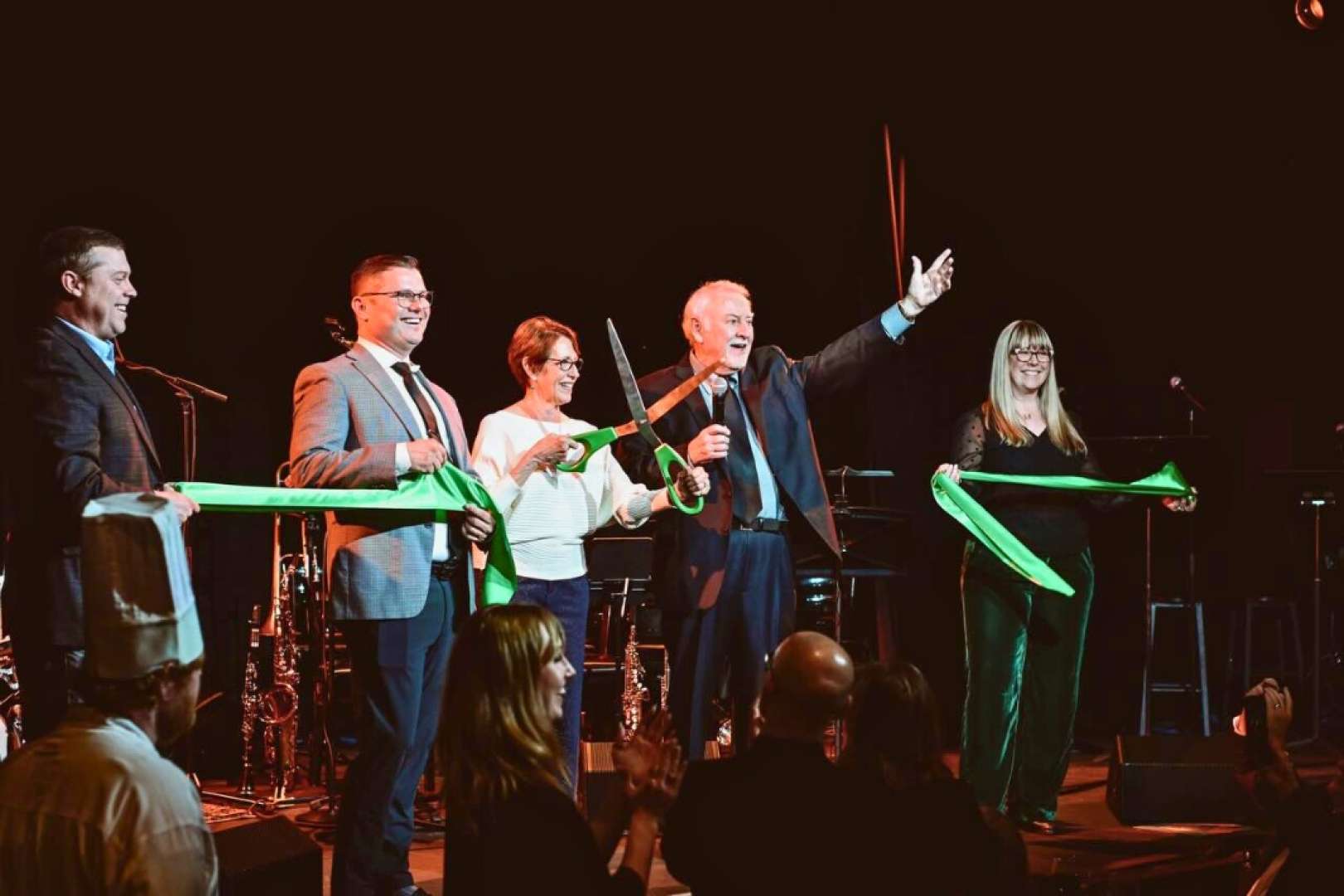 Photo of Co Owners Steve Peters and Connor Delaney cut the ribbon on stage with Des Moines Mayor Connie Boesln