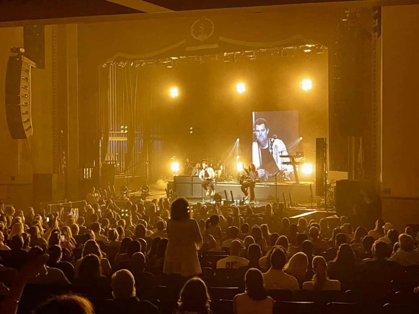 Photo of A performance on stage with a full house.