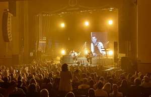 Thumbnail photo of A performance on stage with a full house.