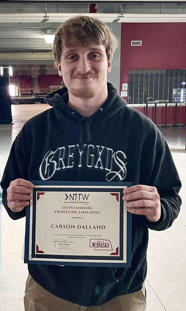 Photo of Carson Dalland holding his outstanding frontline employee award from Visit Nebraska
