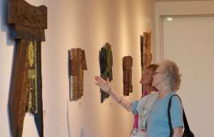 Thumbnail photo of Two women at the Ames Center Art Gallery Exhibition looking at sculpture on the wall