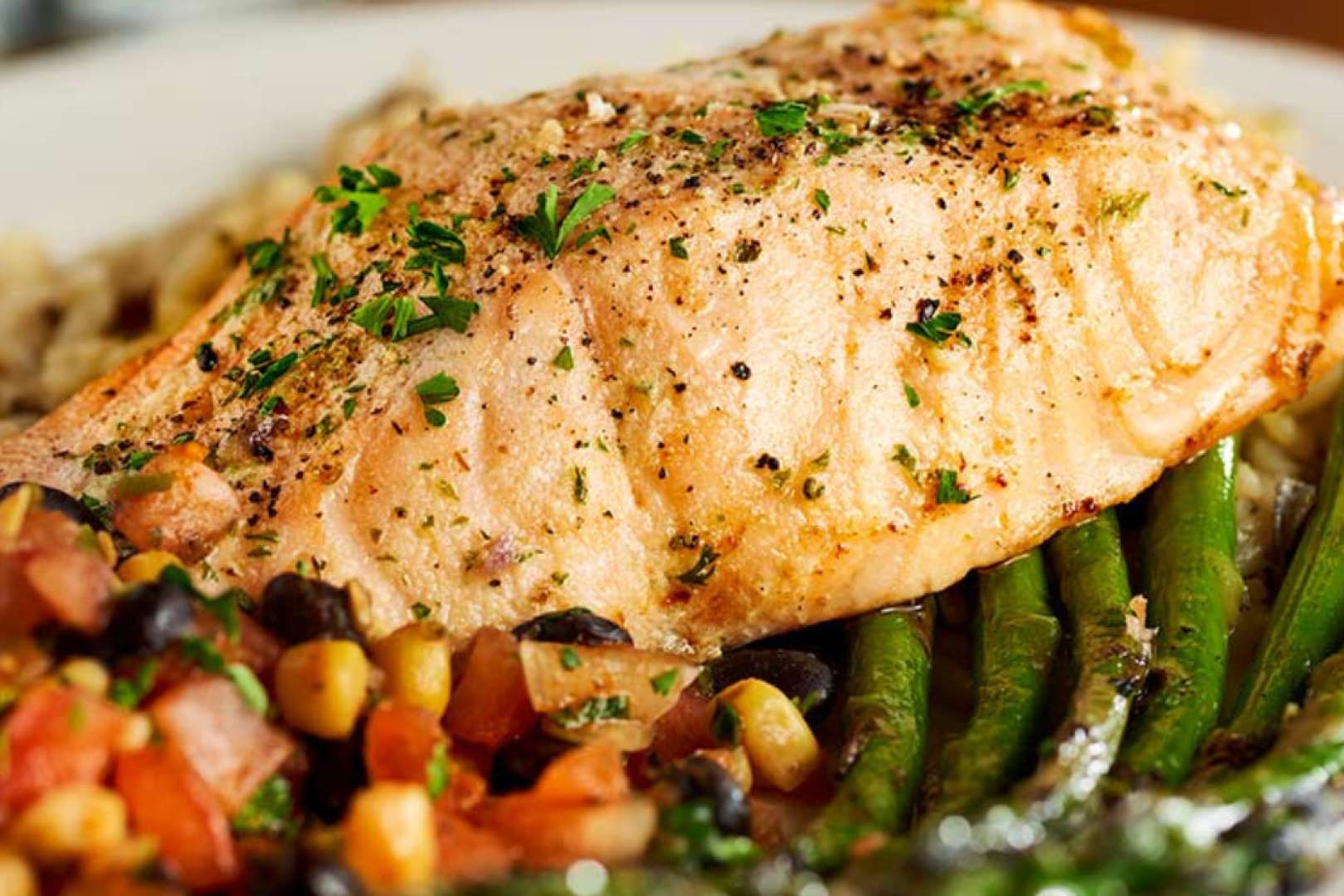 Photo of white fish over a bed of green beans and corn