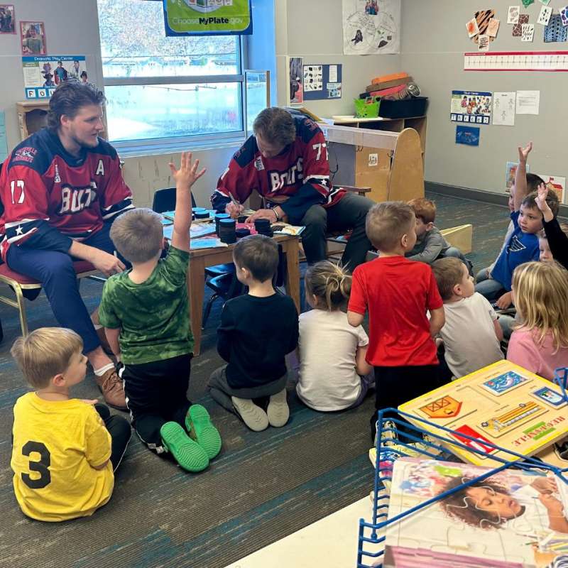 ice hockey team members reading to small kids