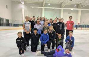 Thumbnail photo of Group of children and a coach posing for a photo on the ImOn Ice Rink