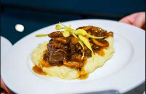 Thumbnail photo of Beef short ribs over a bed of mashed potato on a white plate