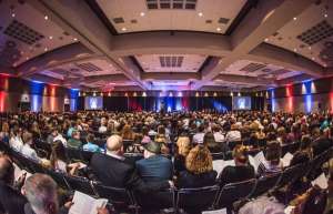 Thumbnail photo of Audience watching the stage at a conference in the One National Events Plaza