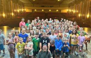 Thumbnail photo of A smiling group of children poses on stage during a summer camp session at the Paramount Theater of Ashland