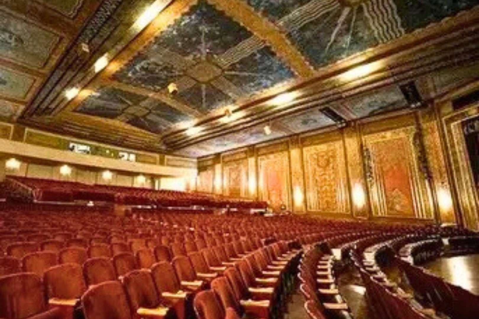 Photo of Inside the historic Paramount Theater of Ashland, ornate ceilings soar above rows of red velvet chairs.