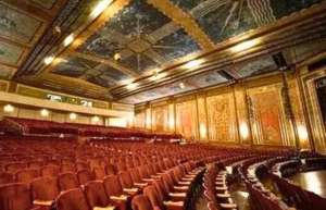 Thumbnail photo of Inside the historic Paramount Theater of Ashland, ornate ceilings soar above rows of red velvet chairs.