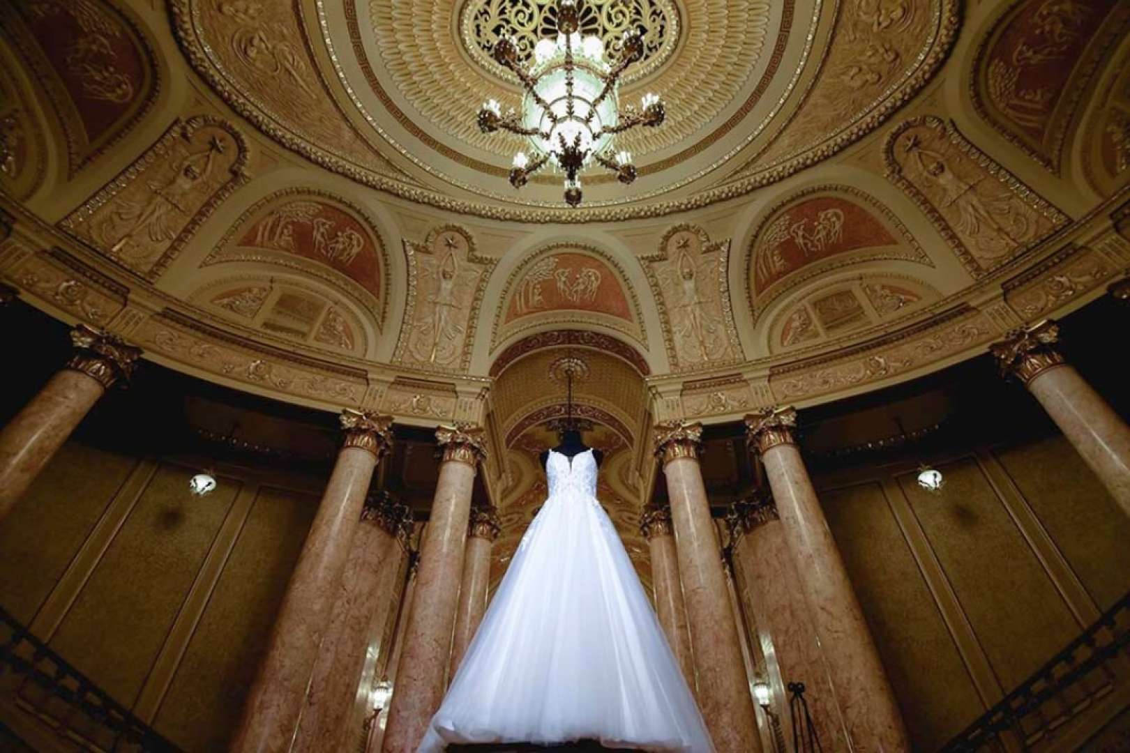 Photo of Wedding dress hanging below the duchess chandelier in the lobby of the Rialto square theater