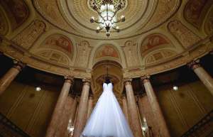 Thumbnail photo of Wedding dress hanging below the duchess chandelier in the lobby of the Rialto square theater