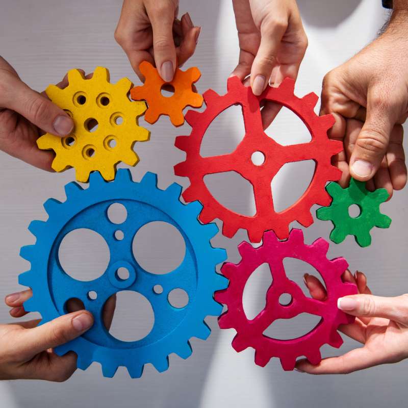 6 hands holding cogs in a wheel together