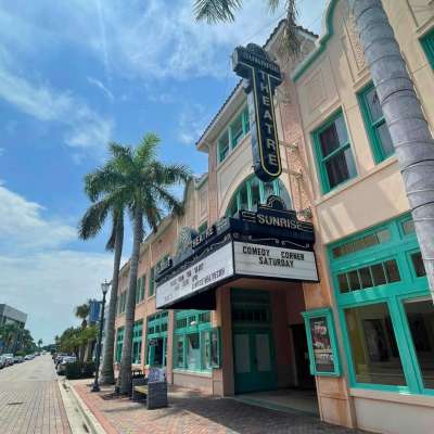 External shot of the Sunrise Theatre in Fort Pierce taken during daytime. Theatre entrance is flanked by palm trees.