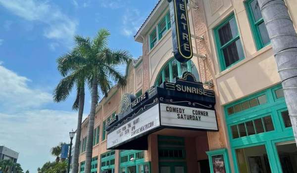External shot of the Sunrise Theatre in Fort Pierce taken during daytime. Theatre entrance is flanked by palm trees.