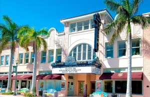 Thumbnail photo of External shot of the Sunrise Theatre in Fort Pierce taken during daytime. Theatre entrance is flanked by palm trees.