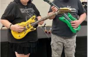 Thumbnail photo of A U.S. Marine Veteran and friend posing with guitars at the Rock of Ages concert in the Oshkosh Arena
