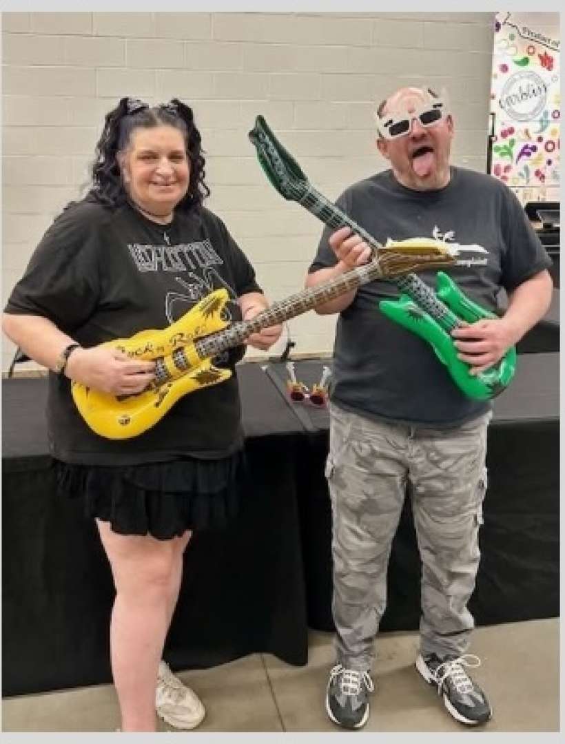 Photo of A U.S. Marine Veteran and friend posing with guitars at the Rock of Ages concert in the Oshkosh Arena