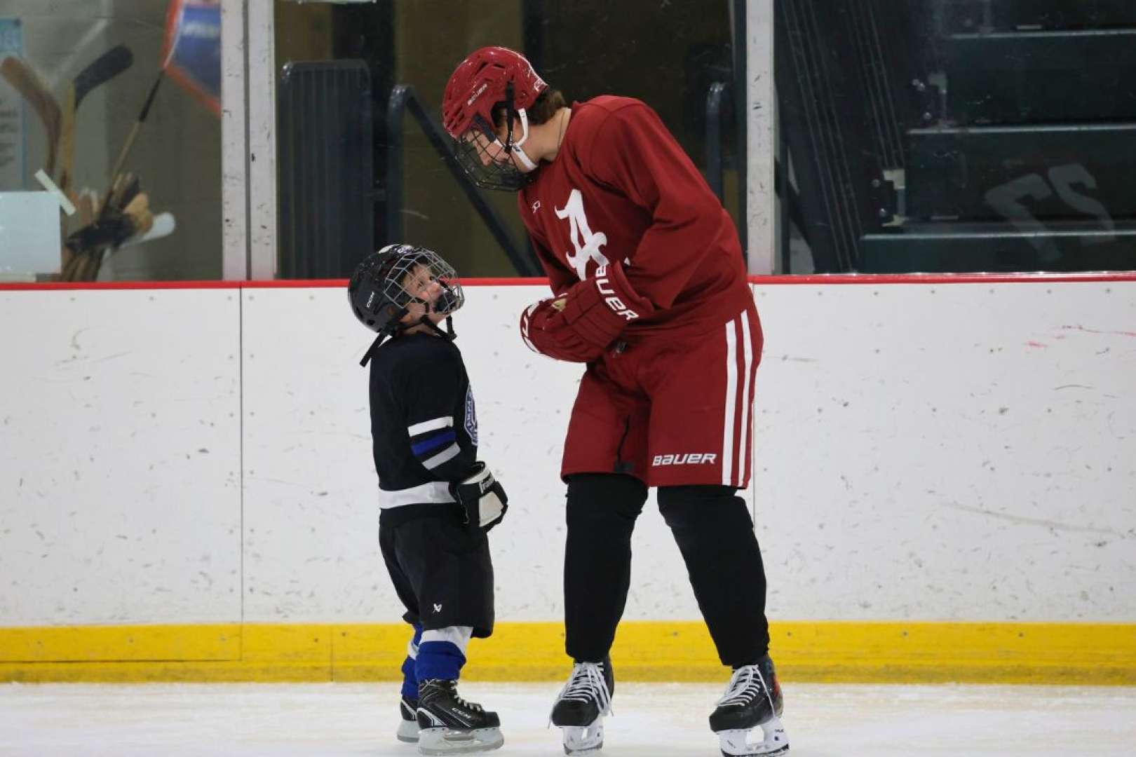 Photo of Young and older hockey players chat on the ice
