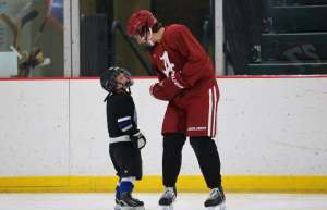 Thumbnail photo of Young and older hockey players chat on the ice